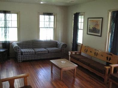 Cabin living room with couch, three person bench, coffee table and chairs.