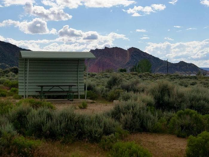 Picnic table with a shelter covering one side and over head.