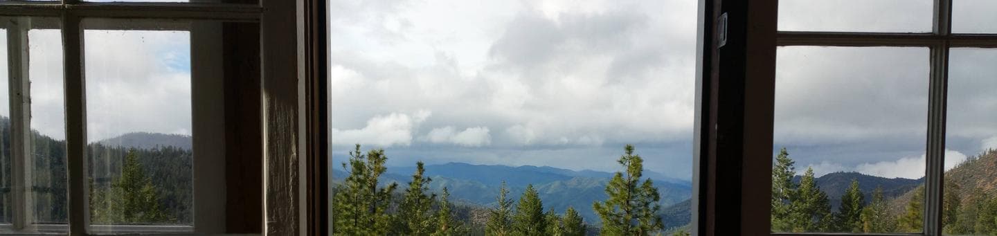 View of mountains and cloudy sky through cabin window.