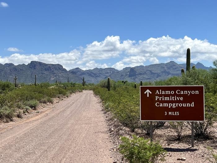 A road sign points down a road to the mountains.