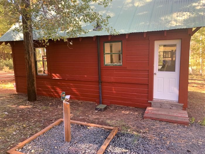 View of the rear of the guard station, facing the back door. A water faucet is in the foreground and the Aspen leaves in the background are starting to turn yellow.