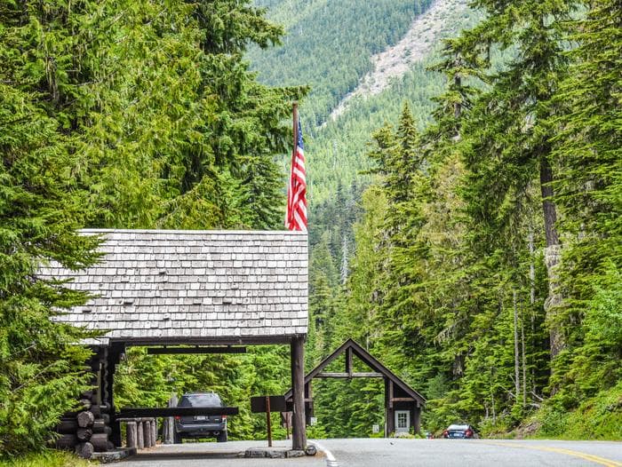 White River Entrance Station with wooden cabins on a highway with one building flying an American flag