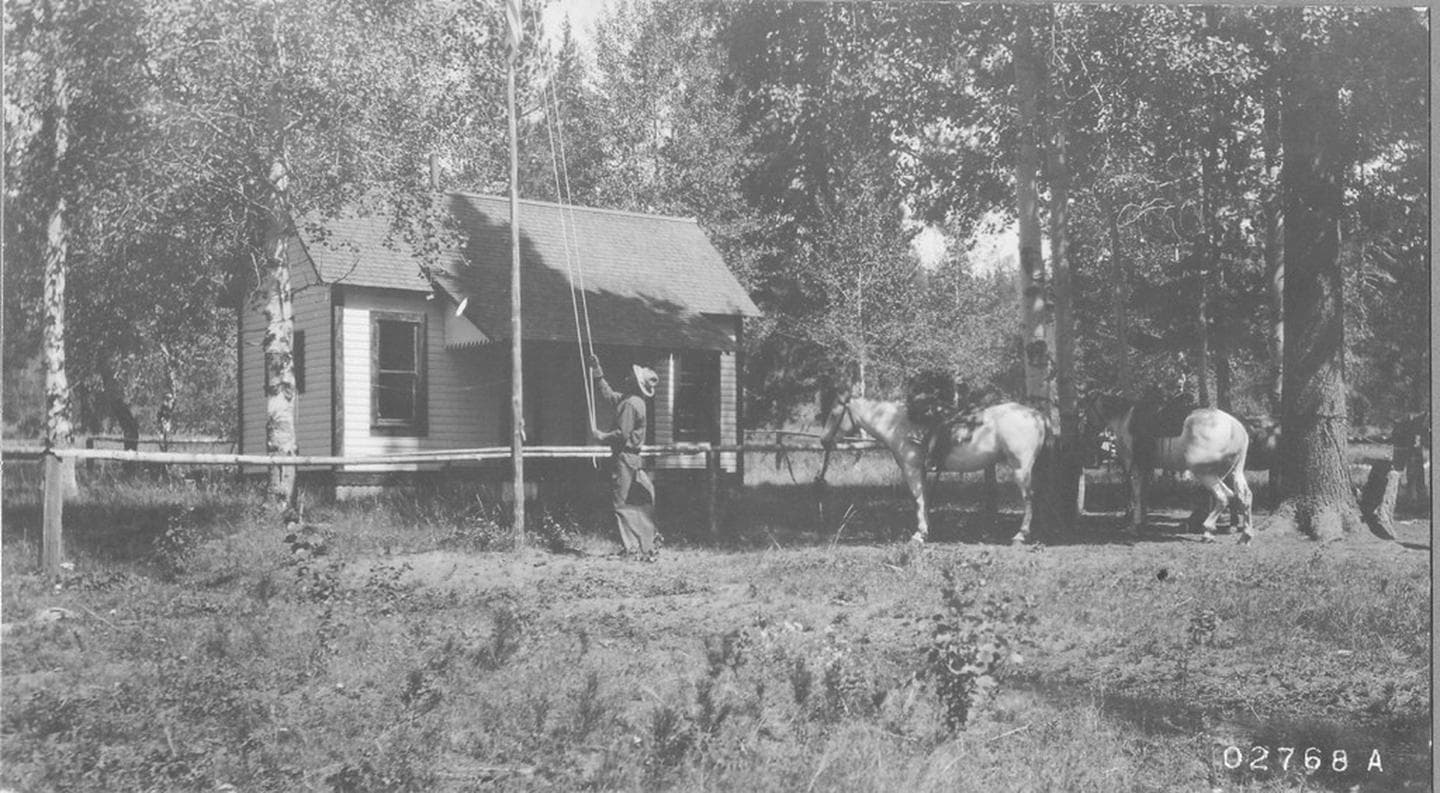 person raising flag in front of cabin