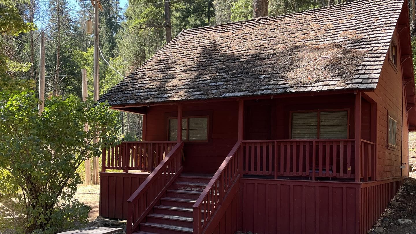 Portion of roof and porch of old, red cabin.