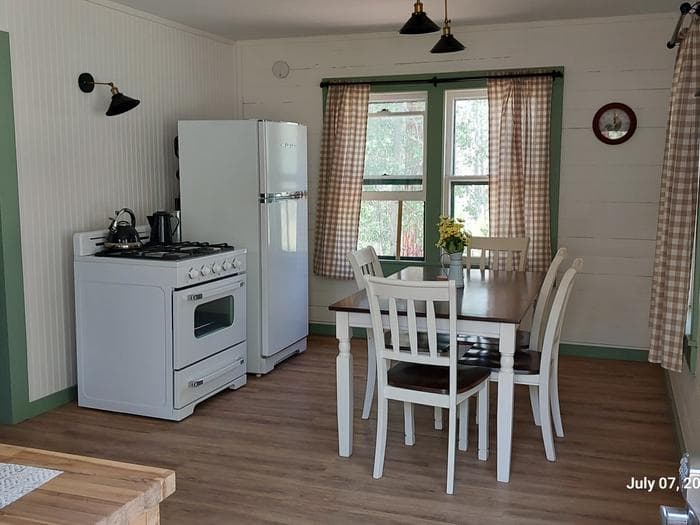 View entering from the back door looking into the Kitchen. Stove, refrigerator and kitchen table are in the center of the photo.
